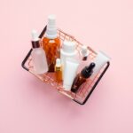 Shopping basket full of cosmetic bottles and packaging on pink background, view from above. Cosmetics sale or discount concept.